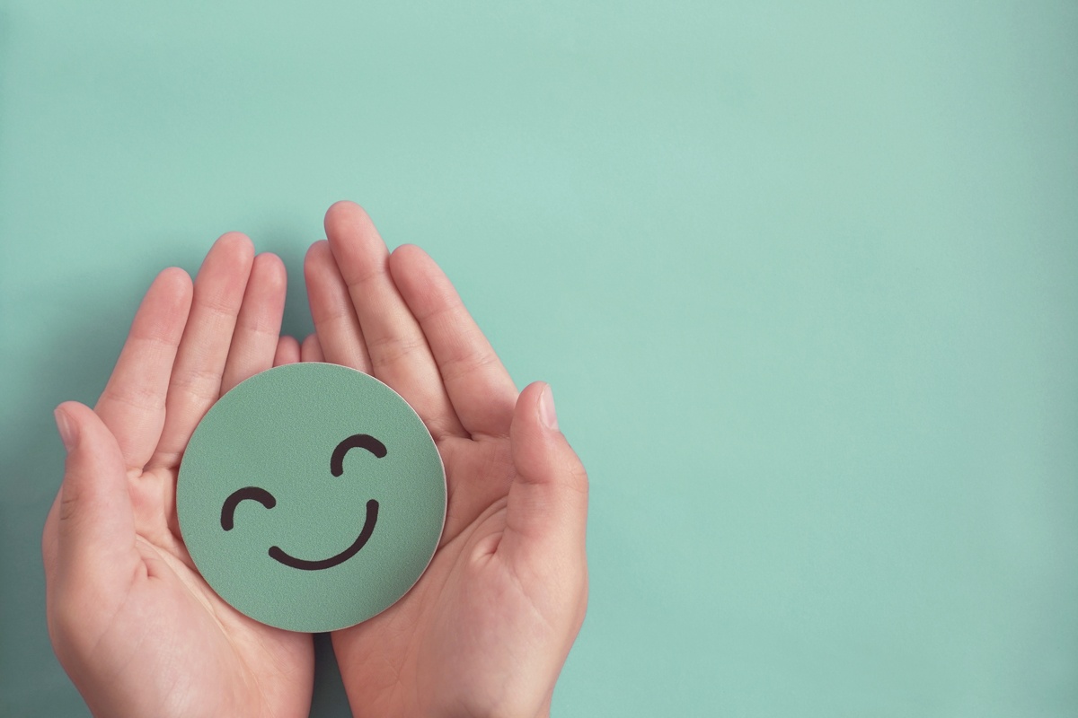 Hands holding green happy smile face, good feedback, rating, positive, mental health, wellness, well-being, share a smile